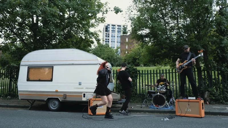 Bears Eat Honey video still: the band playing on a street beside a caravan